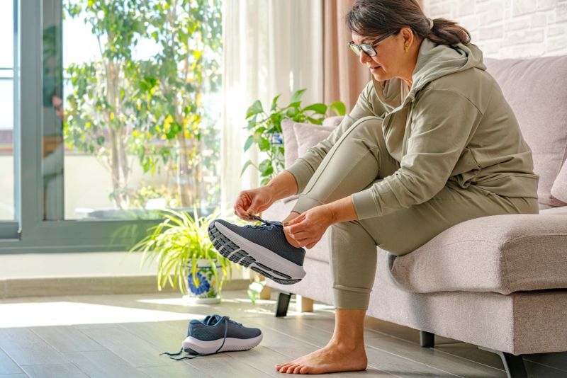 Woman tying athletic shoe wellness home