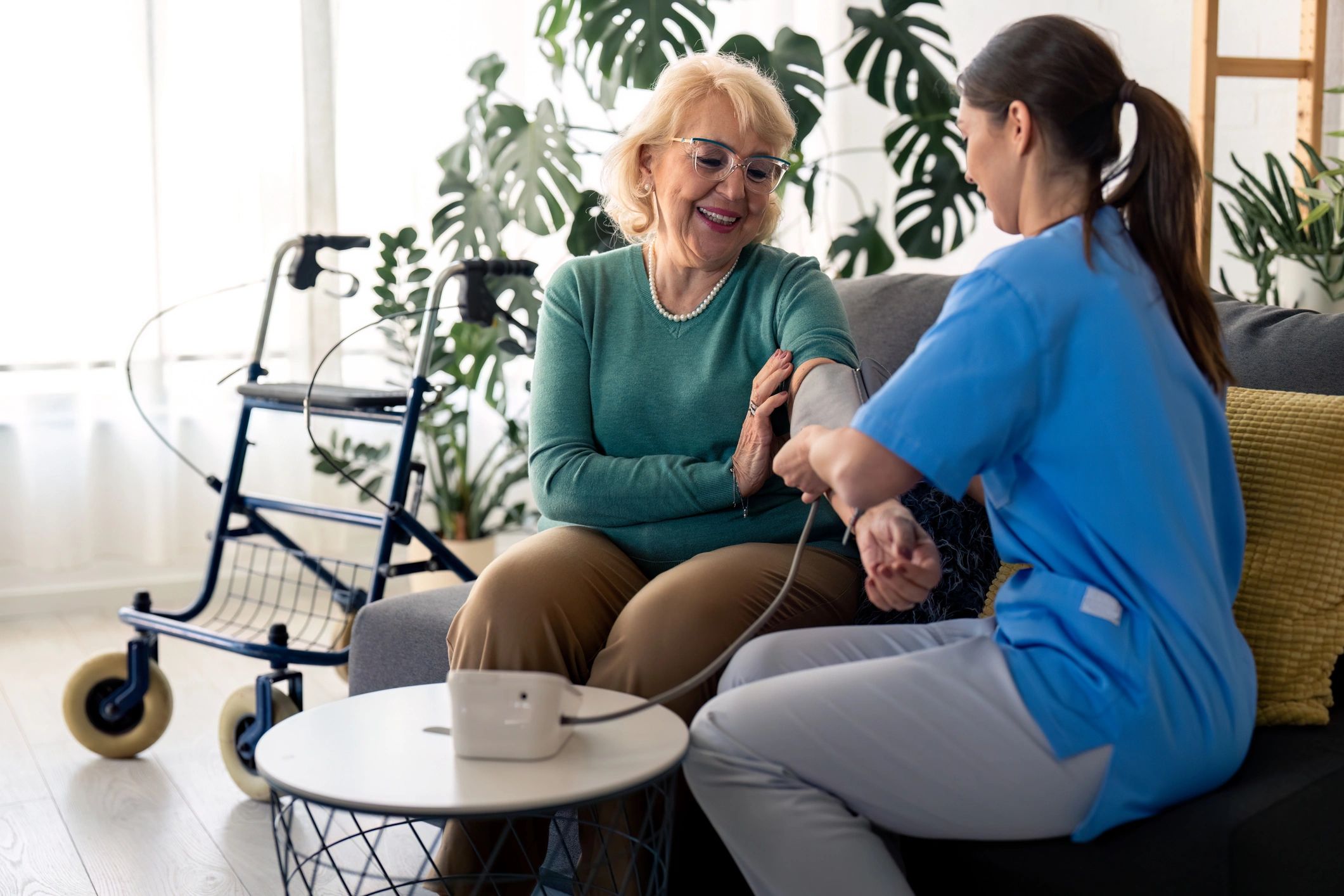 Healthcare provider taking blood pressure of elderly woman with walker